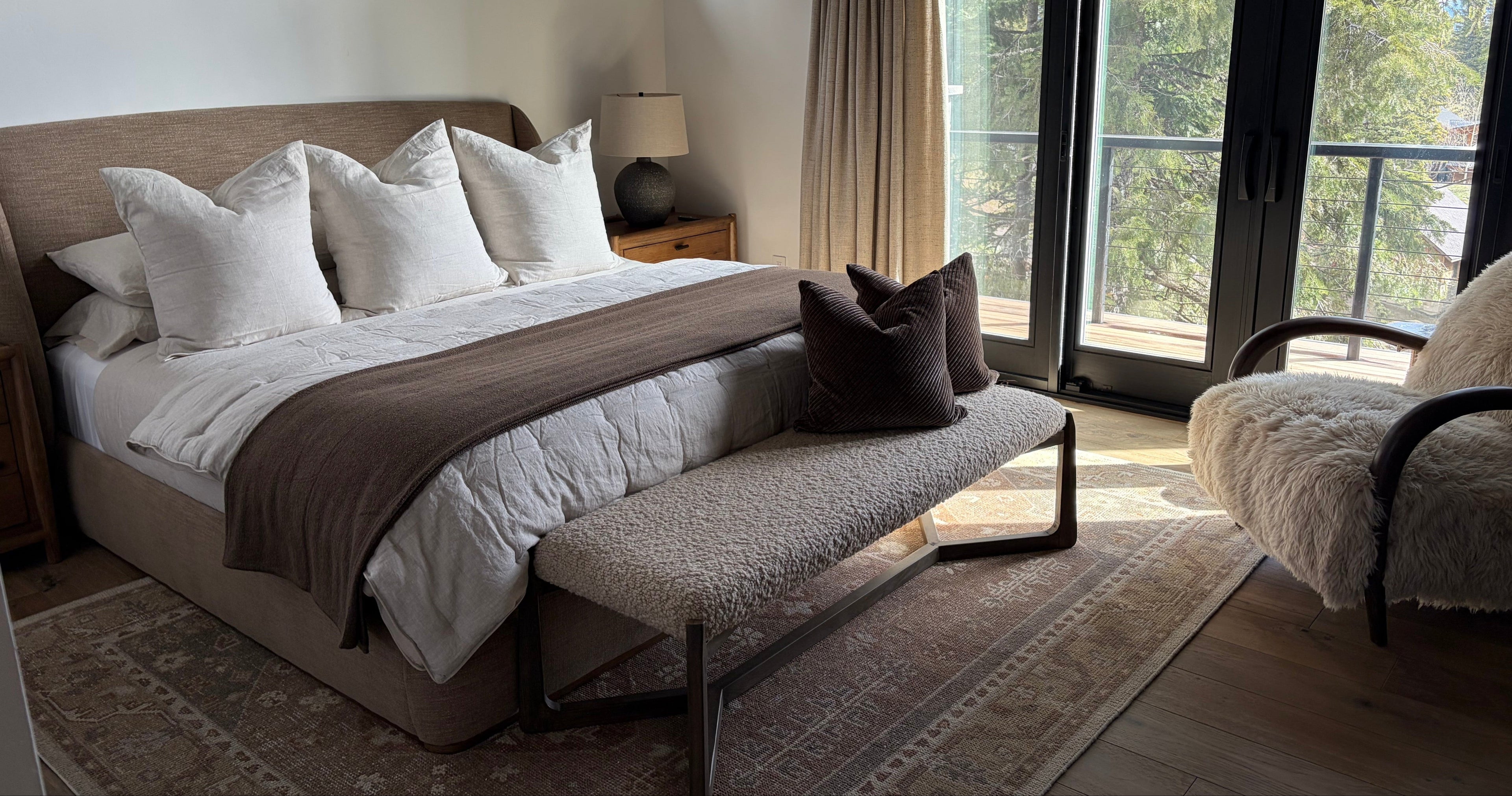 Modern bedroom with a bed, bench, and large window.